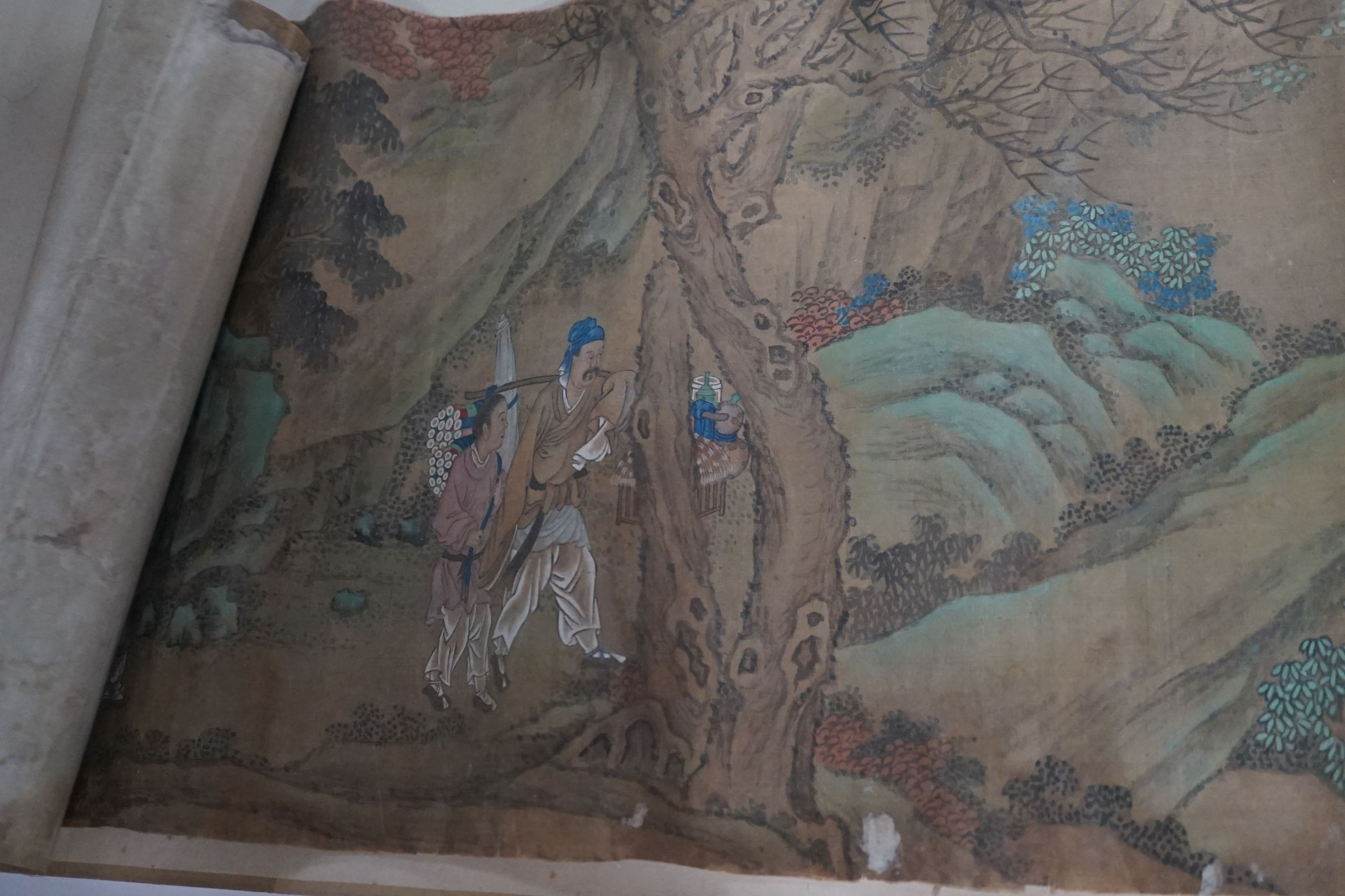 A 19th century Chinese hand scroll painting on silk of figures in a landscape, approximately 206 cm X 32.5 cm